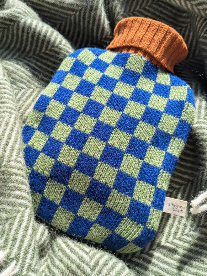COLOURFUL HOT WATER BOTTLE COVER DISPLAYED ON A ON A BLANKET