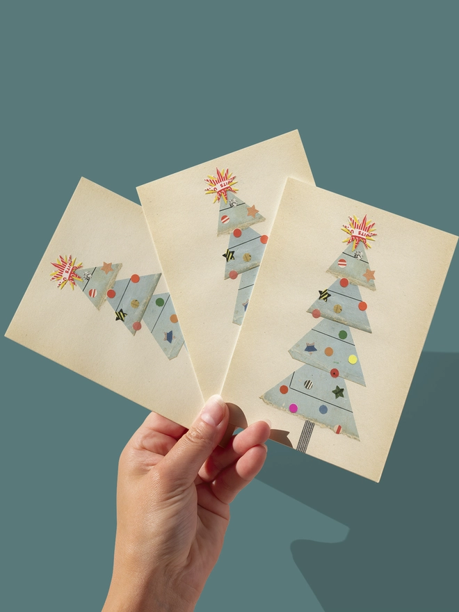 A charming Christmas card featuring a pale blue tree with a collection of eclectic decorations and a large star on top.