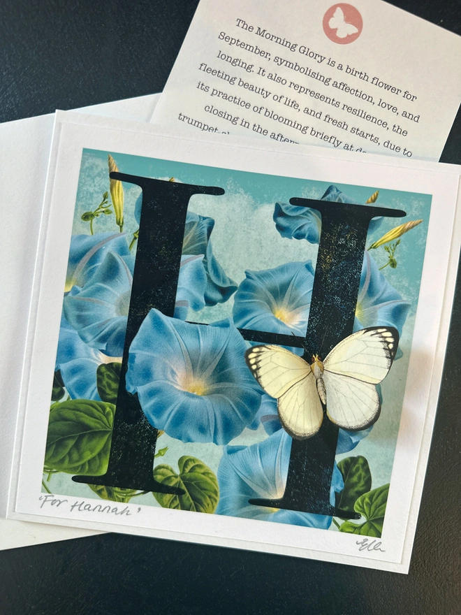 A handmade, personalised September birthday, Butterflygram card, showing a letter H on a floral background, showing the morning glory flower. It is a blue trumpet flower.