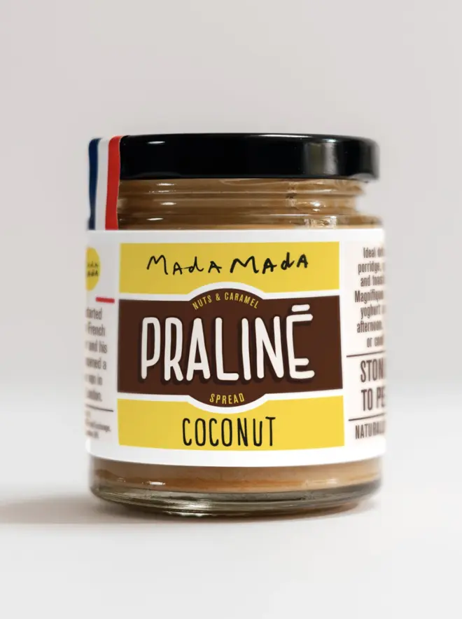 jar of coconut praline nut butter spread with brown and yellow label, and black lid