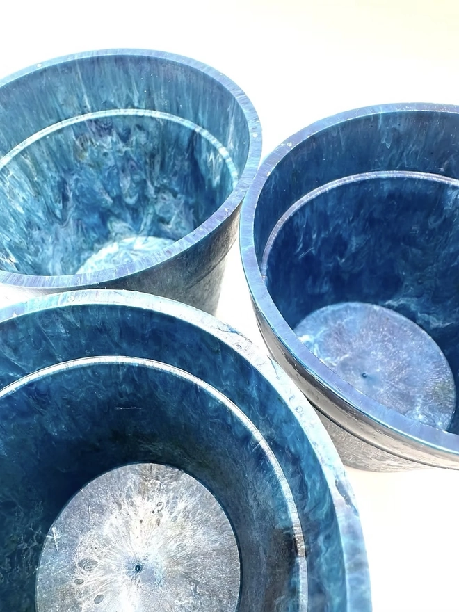 Small Blue Ocean Plastic Plant Pot , a collection of blue recycled pots sitting on a white surface against a plain backdrop. 