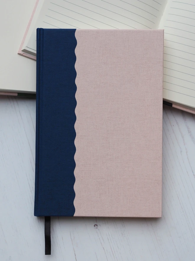 a two tone hardcover notebook with a scallop design in navy and blush