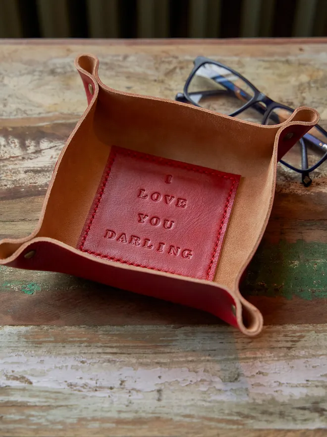 I love you darling leather coin tray. A square leather coin tray with a red square on the bottom stamped with the phrase 'I love you darling'