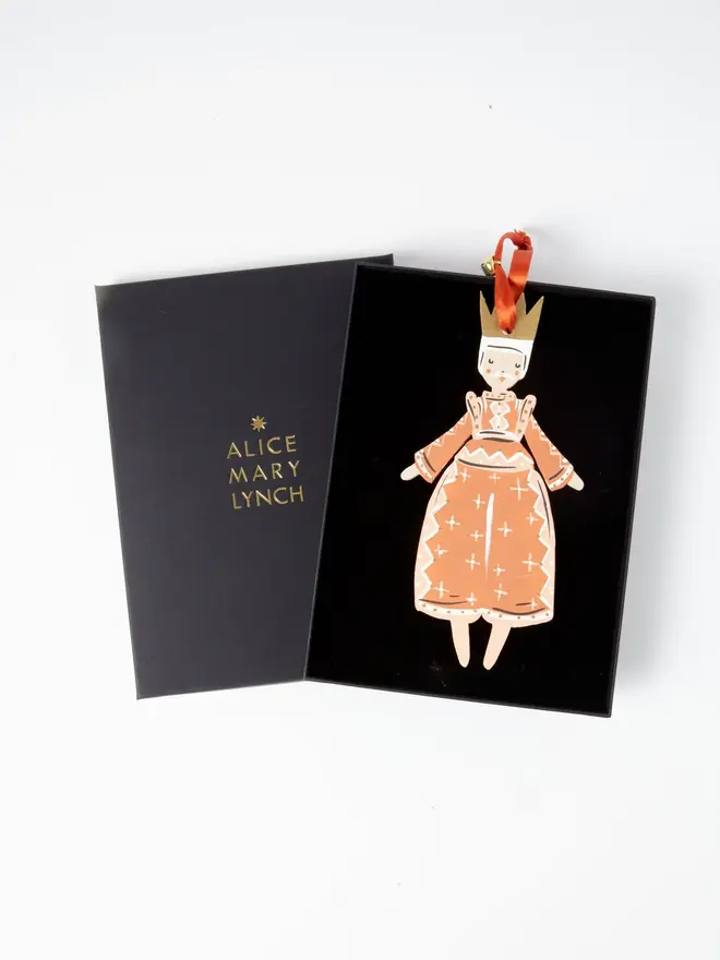 Prince Tree Dancer. wooden hanging prince decoration in an open black gift box embossed "alice mary lynch" in gold, with terracotta robe, gold crown and orange ribbon with a jingle bell