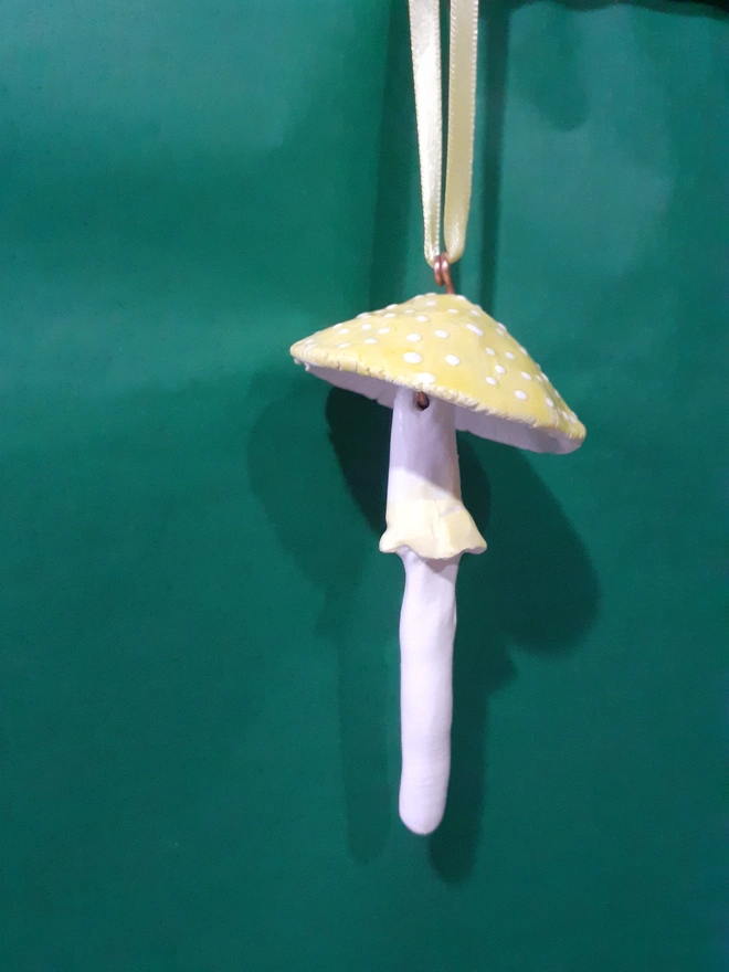 Handmade ceramic yellow toadstool hanging decoration with white polka dots and a matching yellow satin ribbon.
