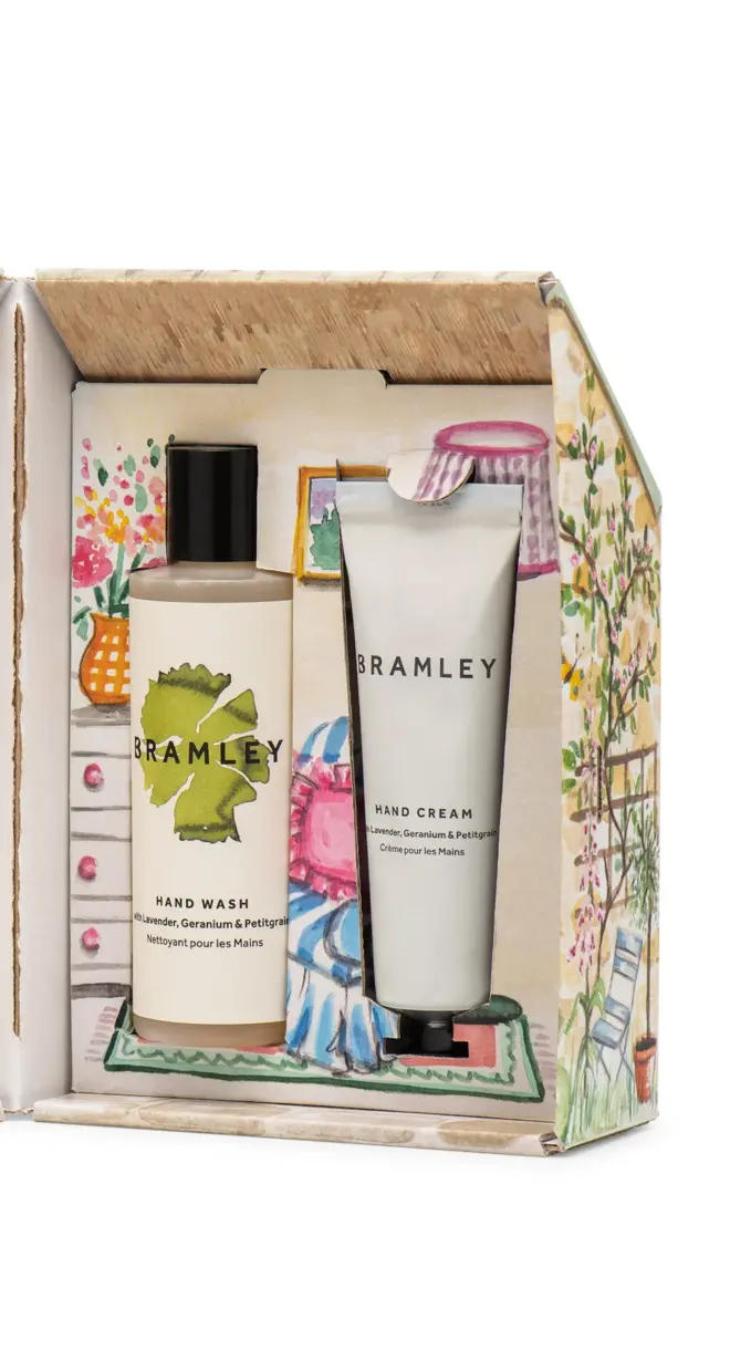 interior of cardboard cottage, holding one bottle of hand wash with a white and green label and black lid, and one white tube of cream with black lid