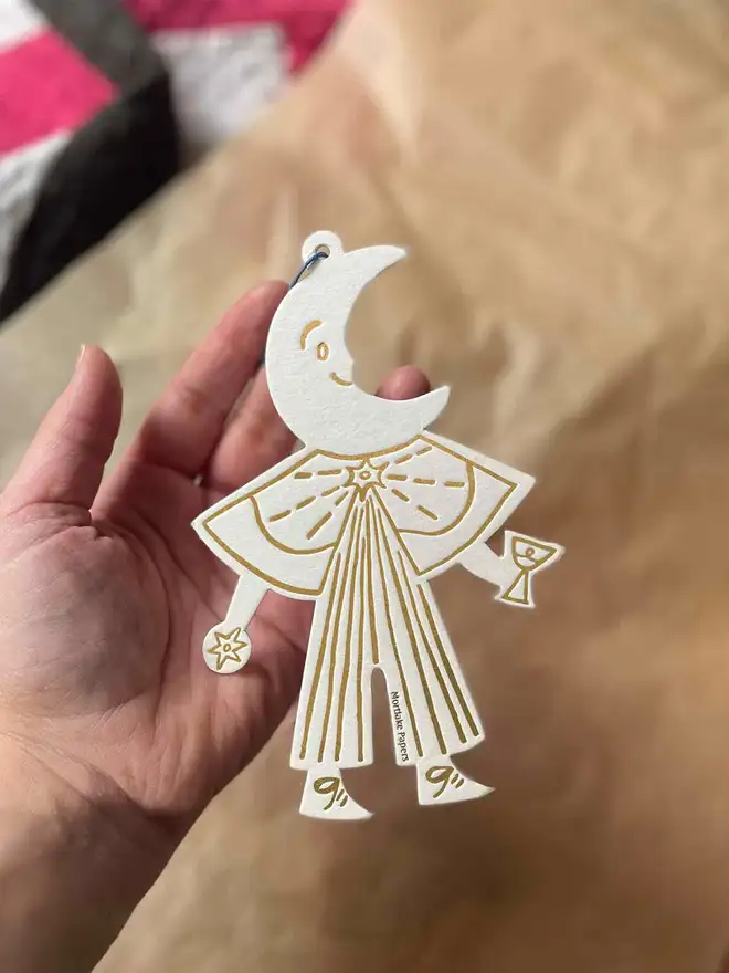 gold and white moon Christmas decoration held in hand
