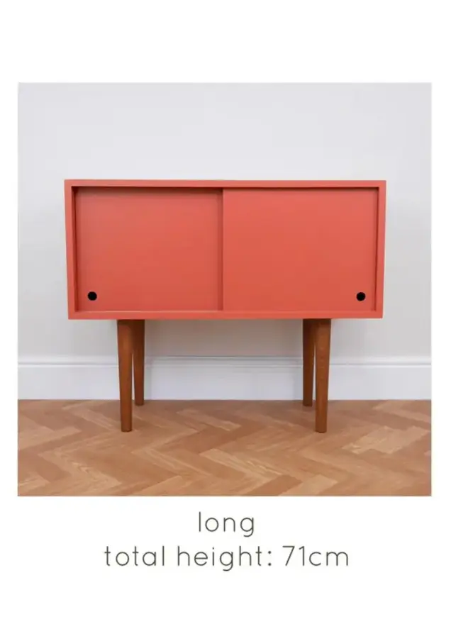 Mid-century cabinet with coral sliding doors and wooden tapered legs.