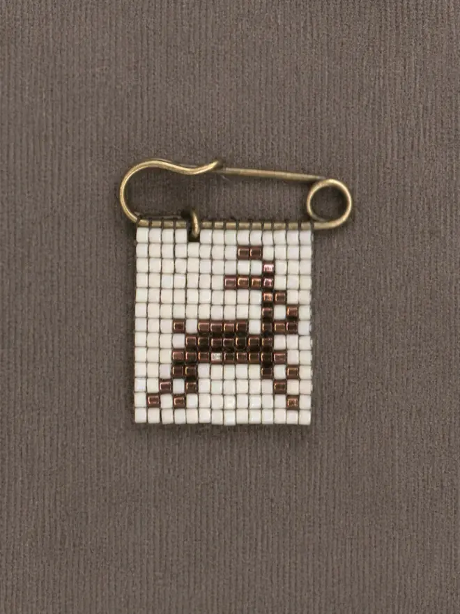 tiled beaded rabbit pin. a beaded pin badge with a brown rabbit on a pearl background.