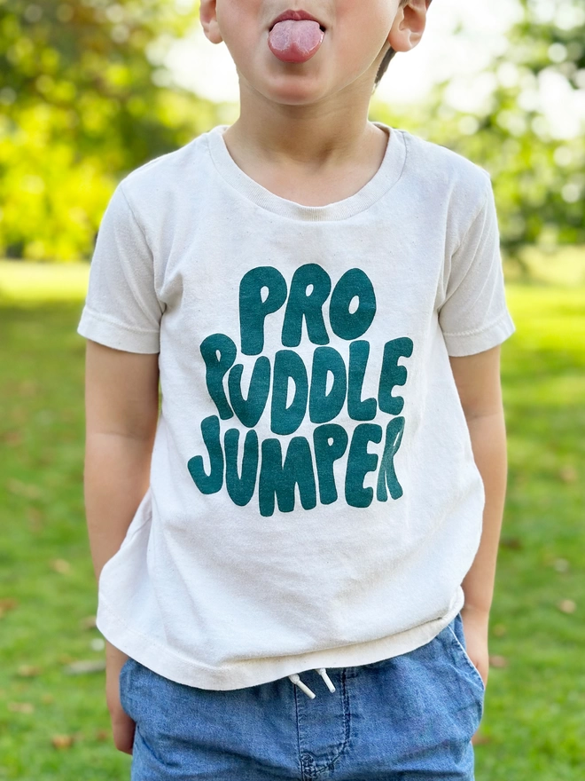 Young boy wearing an organic cotton t-shirt with the words pro puddle jumper printed in teal green ink