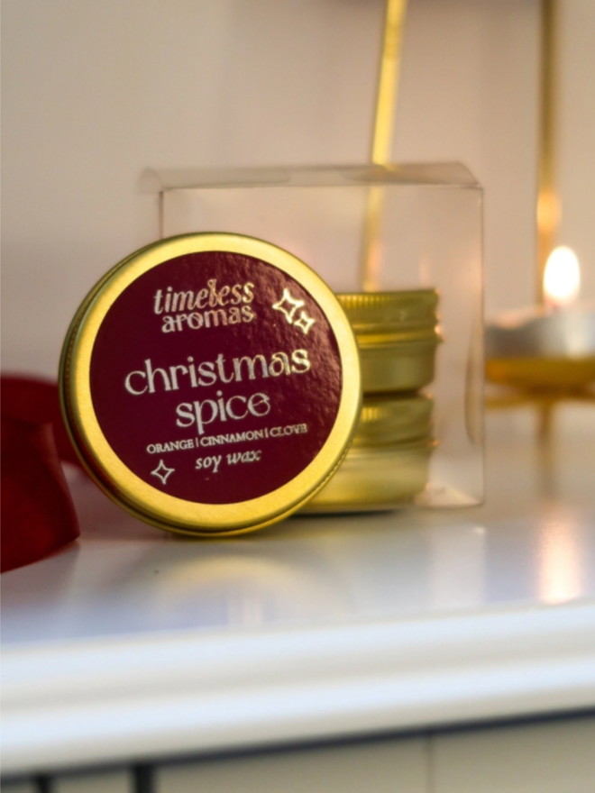 personalised calligraphy christmas crackers. a soy candle in a round gold tin.
