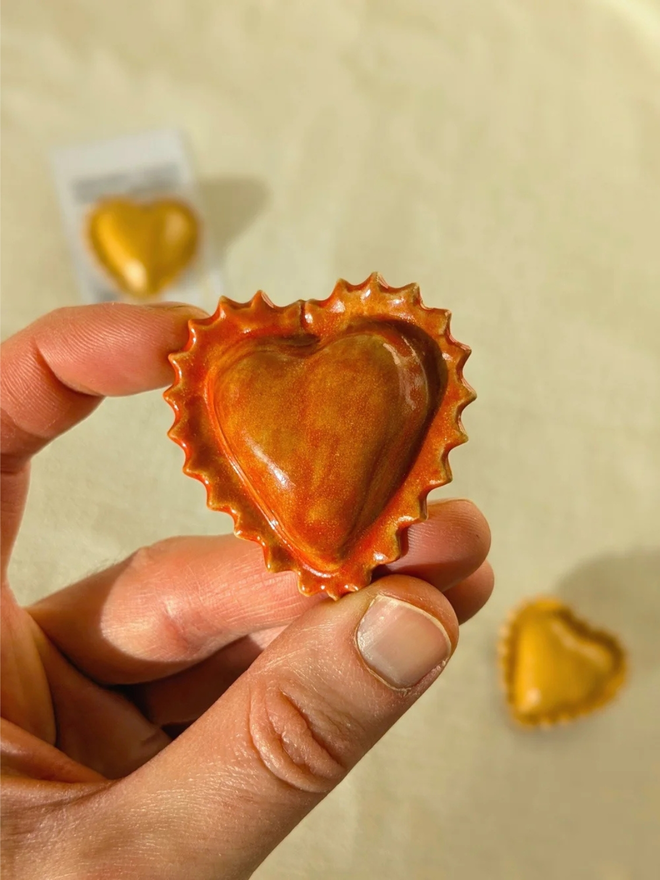 ceramic pasta magnet. a ceramic heart-shaped ravioli magnet on a fridge door.