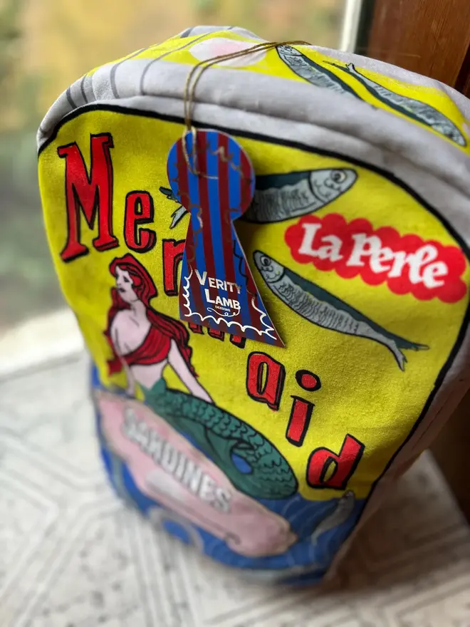 Mermaid Tin Cushion, a decorated mermaid cushion sitting on a window sill. 