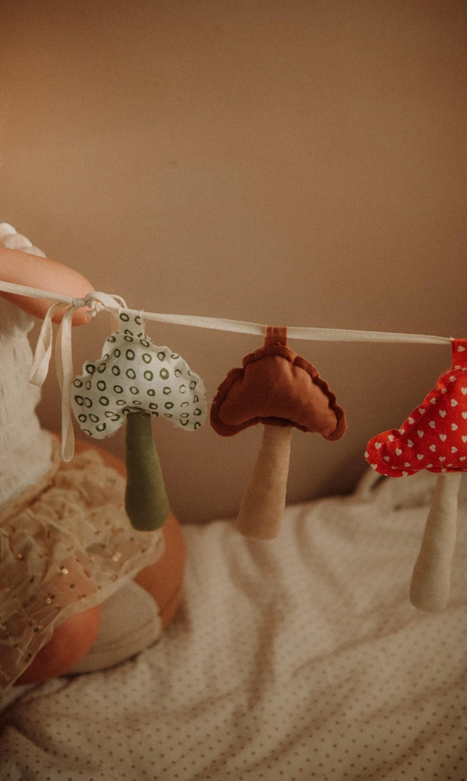 Mushroom Garland Decoration, a child playing with their hanging mushroom bunting in their bedroom.  