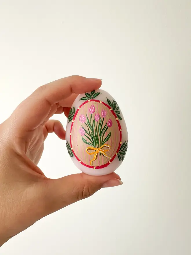 Hand Painted Easter Egg Candle Pink Tulips, a pink Easter egg candle held by a woman in front of a plain backdrop. 