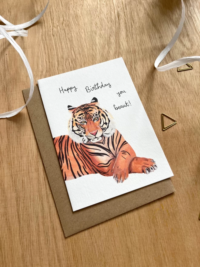greetings card featuring a tiger with their front paws crossed with the phrase “happy birthday you beaut”