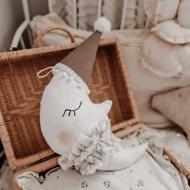 Hanging Moon Pillow Decoration, a hanging moon pillow decoration sitting in a wooden hamper amongst other bed accessories. 