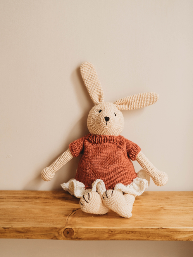 hand crochet bunny rabbit with red and white hand knit dress on wooden shelf