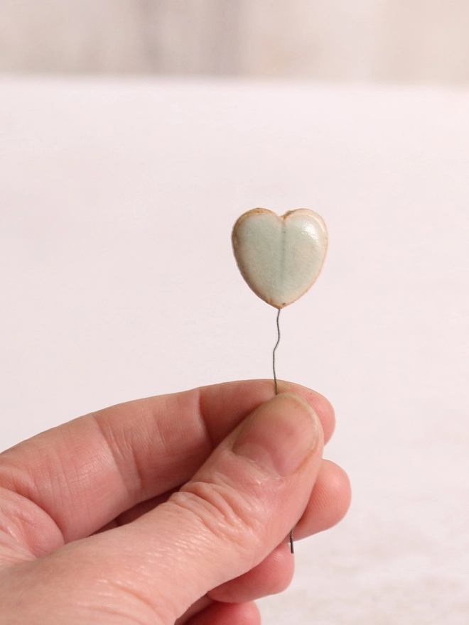 heart shaped ceramic leaf held between thumb and finger