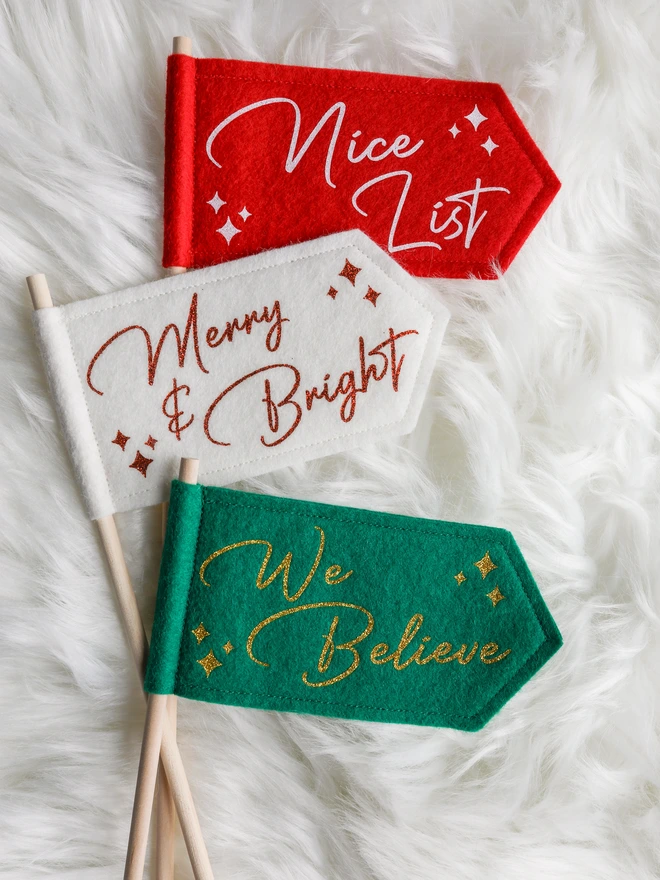 Felt Christmas flags on wooden sticks. Red, Holly or white options with a cursive glitter text.