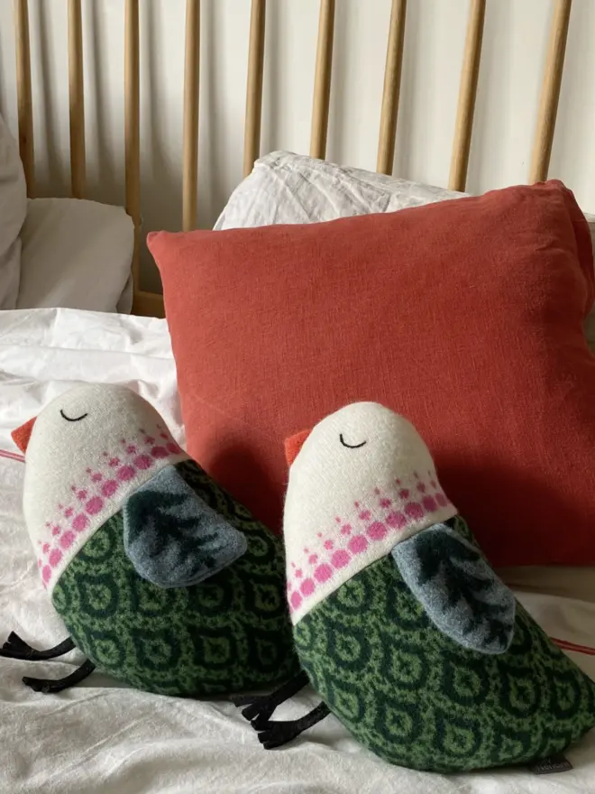 two green bird plushes on a bed
