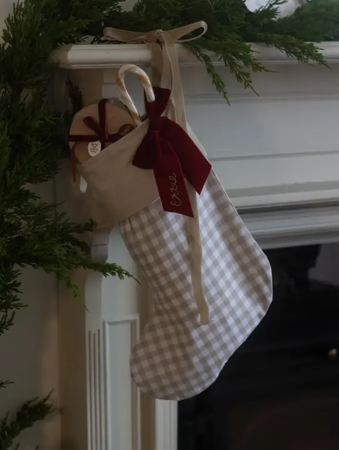 beige gingham stocking with dark red velvet bow, embroidered with a name