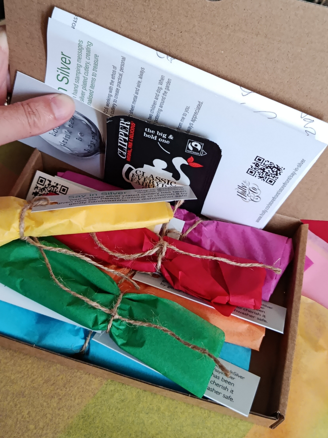 A box of brightly gift wrapped cutlery. 