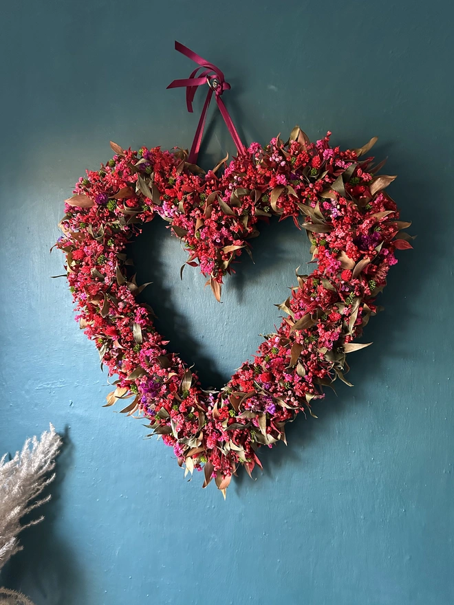 Heart shaped dried flower wreath. Dried red flowers arranged in a heart shape and made into a wreath.