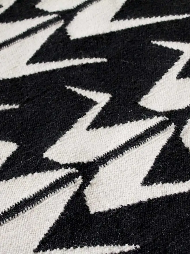 Crane Flatweave Rug, a colourful rug sitting on a plain surface. 