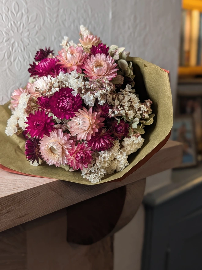Pink flowers wrapped in gold on shelf