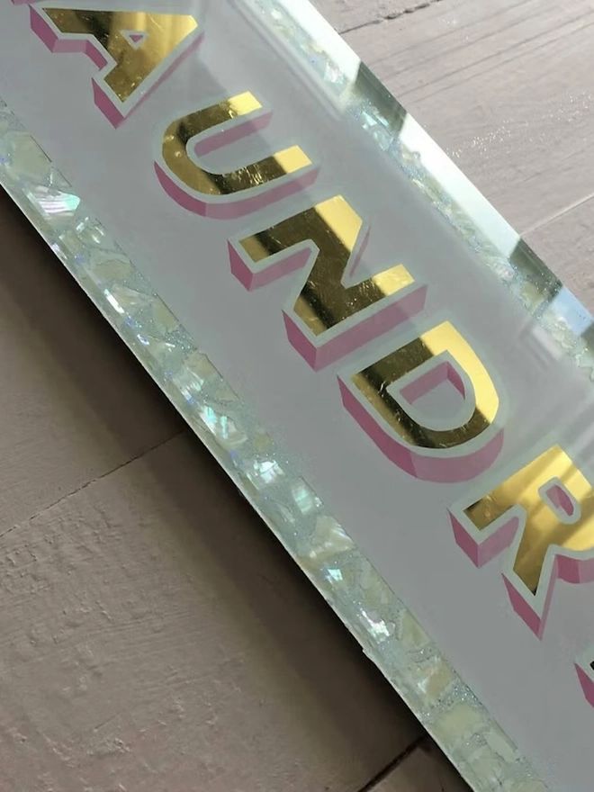 'Laundry' Glass And Gold Leaf Sign, a gold and glass sign sitting on a plain surface. 