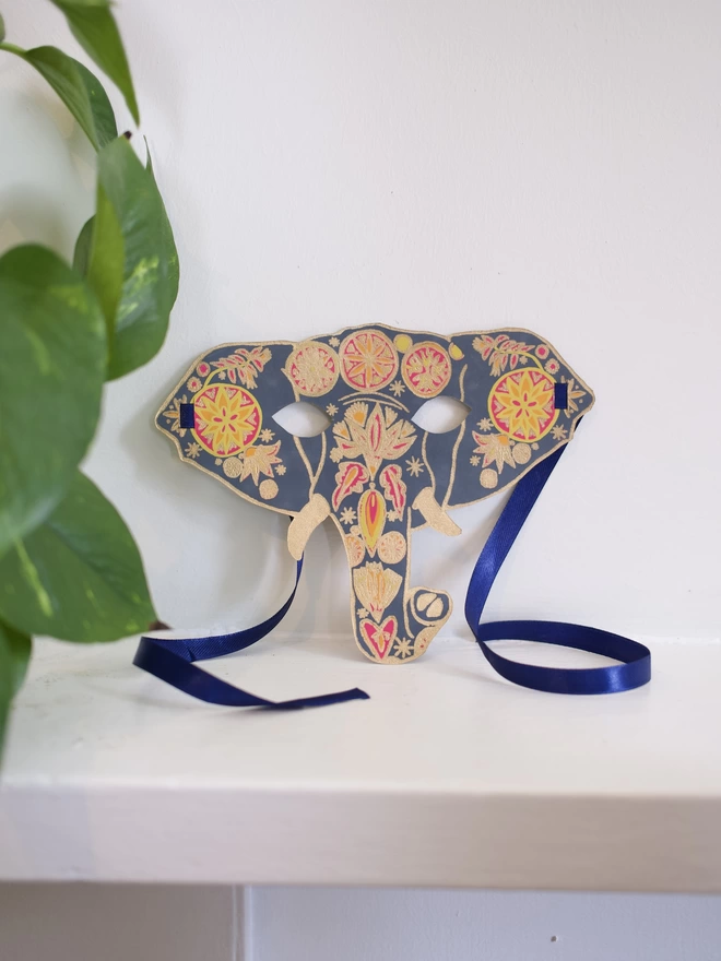 Full shot of image of blue, yellow and gold elephant head and matching blue ribbon