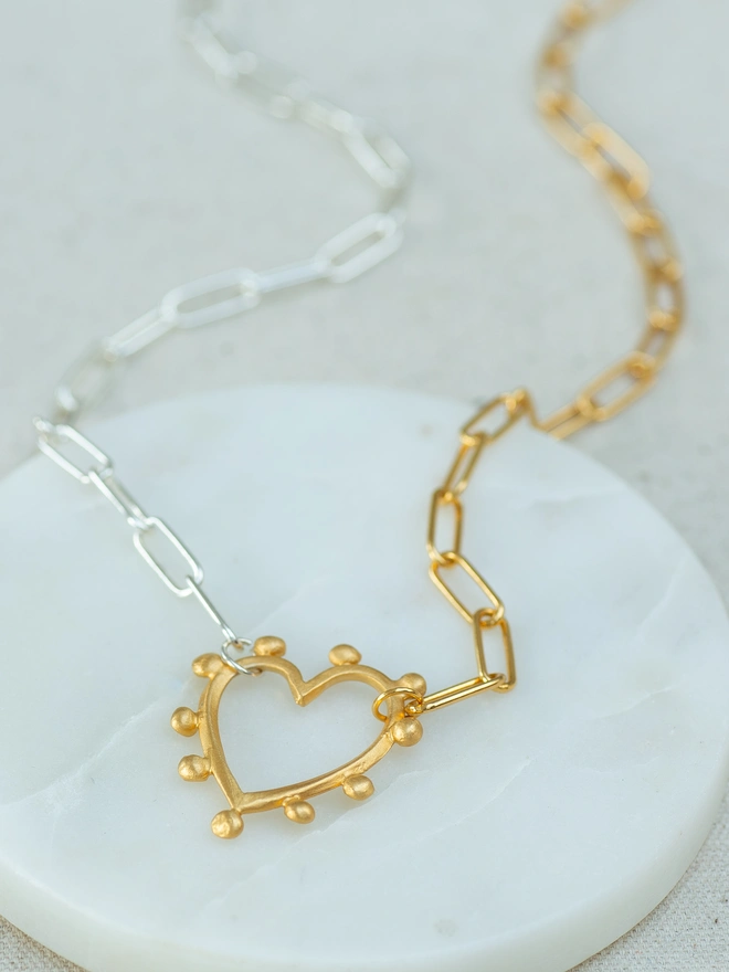 The Large Studded Heart Necklace is a striking statement piece featuring a beautifully textured heart charm on a mixed metal paperclip chain. Designed to balance strength and softness, this bold heart necklace is effortlessly wearable and perfect for layering or styling solo — a modern keepsake that celebrates love, confidence and individuality.