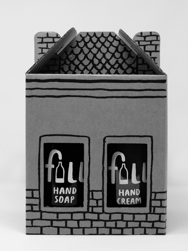 Go Fig & Go Home. A box shaped like a house containing bottles of cleaning products.
