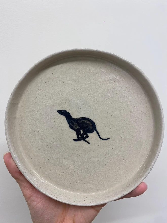 Handmade Ceramic Side Plate With A Black Greyhound Design, a person holding a ceramic side plate with a black greyhound design against a white backdrop. 