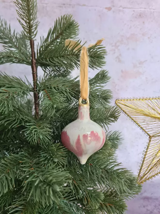 Ceramic christmas bauble decorations in a pearlescent glaze with white, cream and pink and gold, with silk ribbon and gold detailing. Photographed on a pearlescent serving dish with gold pears and christmas lights, gift, christmas, ceramics, pottery, christmas, decorations, christmas tree