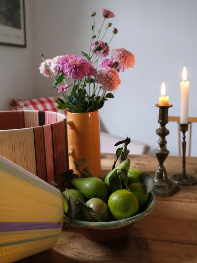 Lifestyle image of Pink and Putty lampshade on table with flowers fruit and candles 