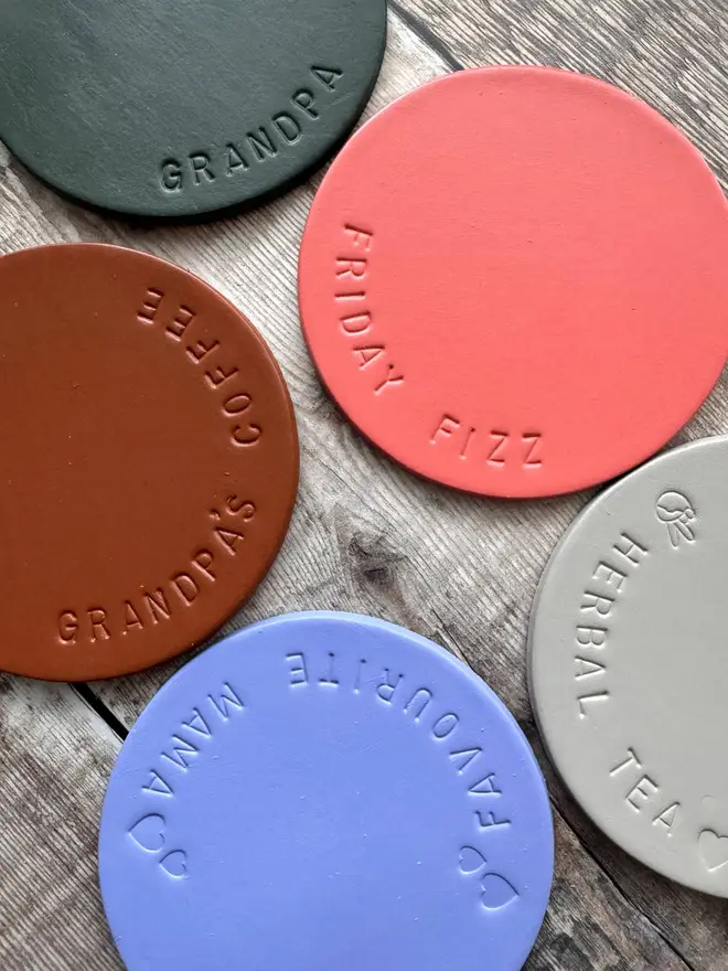 Handmade leather coasters in various colours, embossed with personalised messages like 'Herbal Tea' and 'Favourite Mama.' Stylish and durable drink coasters, perfect for gifts and home decor.