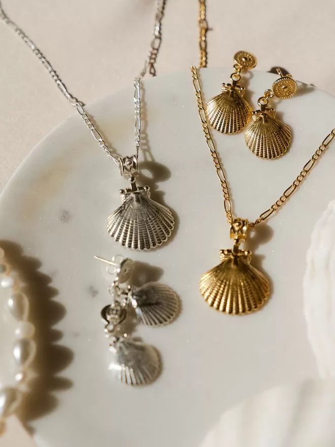 Shell pendants in gold and silver with shell earrings on white background by Loft & Daughter