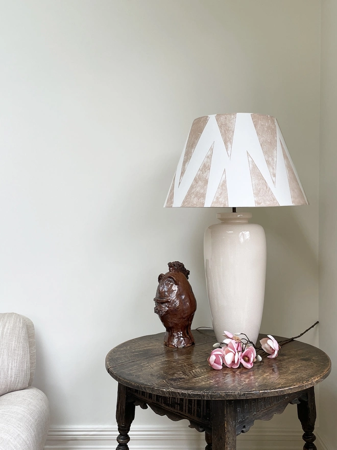 Neutral empire lampshade with bold geometric triangle pattern in soft beige and cream, styled on a ceramic table lamp. A modern geometric lampshade design from Studio Zef, perfect as an empire shade for table lamps, creating a bold yet elegant look in contemporary interiors.