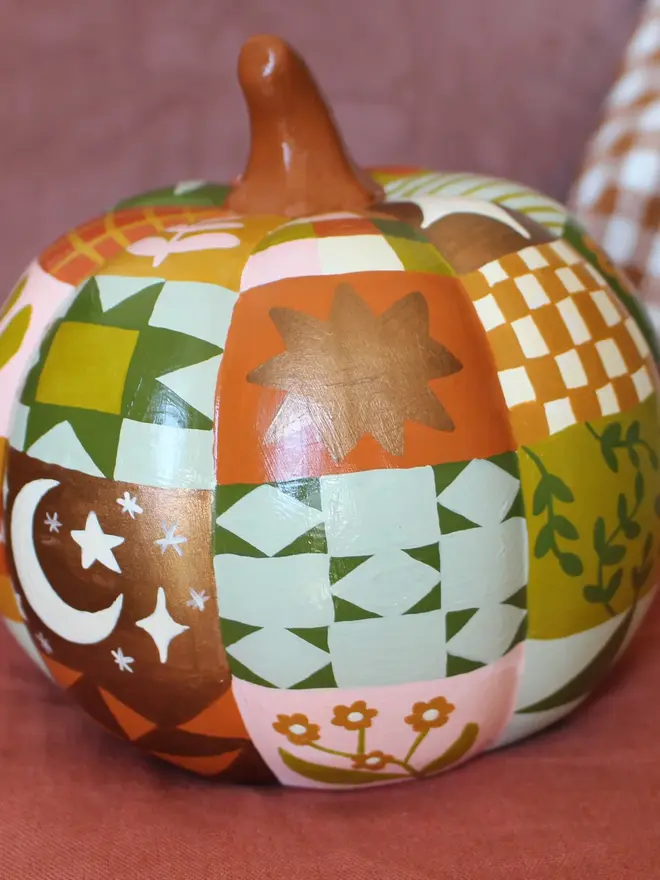 hand-painted woodland ceramic pumpkin. a ceramic pumpkin painted with patchwork colours and patters, alongside mushrooms, moons, stars and flowers.