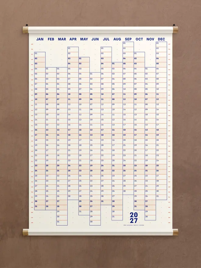 A white 'snow' Dotline 2027 yearly wall planner on brown wall