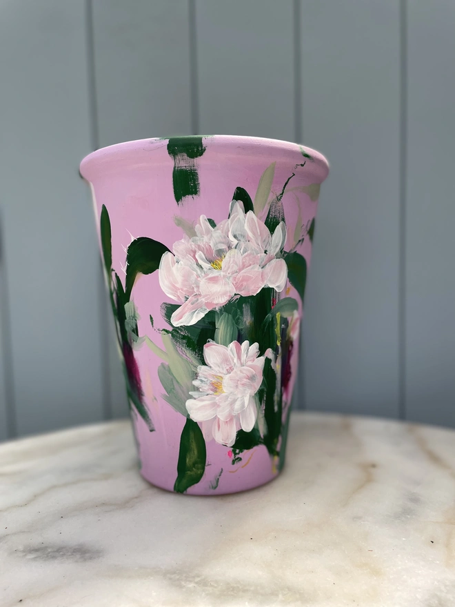 Unique hand-painted terracotta pot featuring pink peonies on a pale pink background