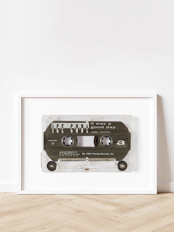 ice cube it was a good day cassette tape print. framed print propped up against white wall on wooden floor.