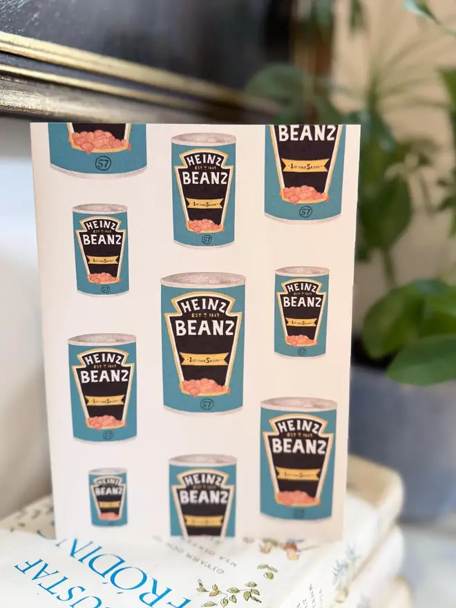 baked beans tins illustrated card. card placed on top of book pile.