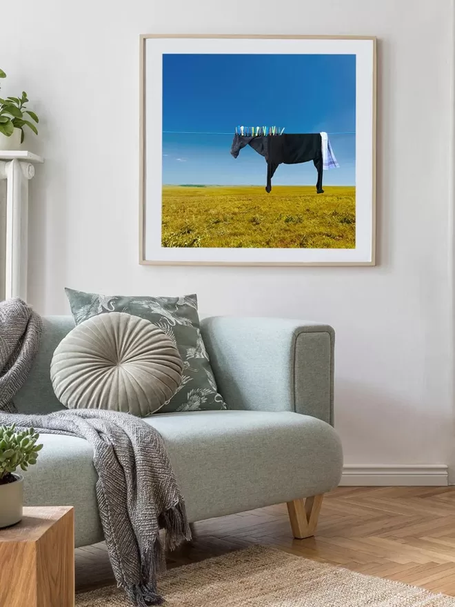 Pegasus the black clothesline horse hanging on a clothes line above a green field seen in a sitting room.