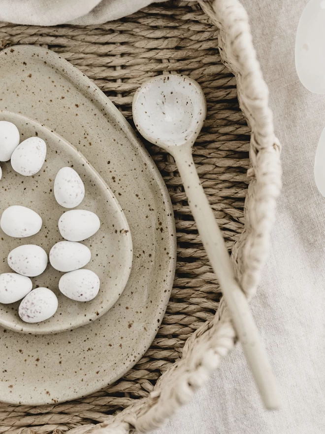 white ceramic spoon laid beside beige coloured egg shape plates