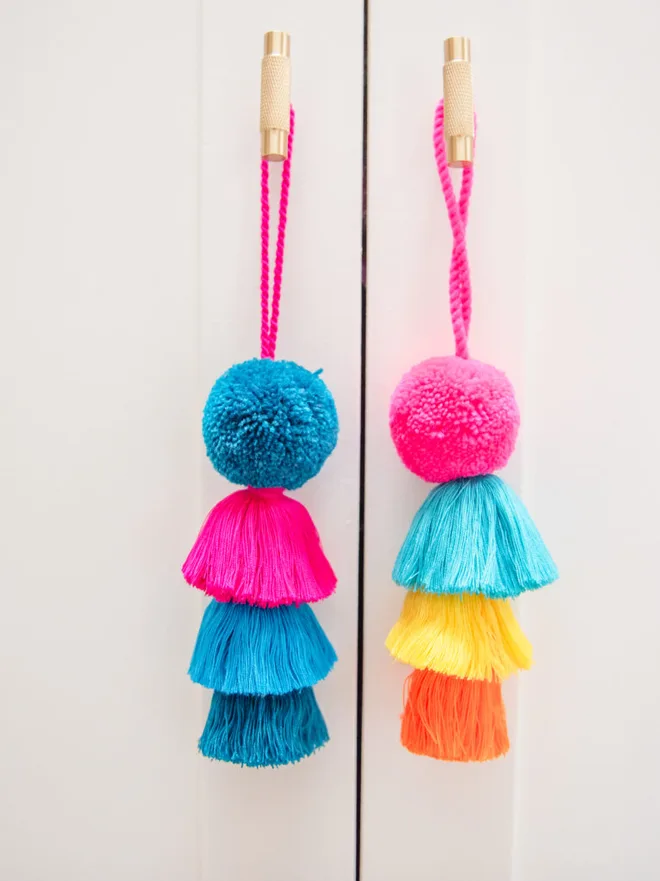 pom pom and tassel swag hanging decoration. multi-coloured pom pom and tassel decorations hung on wooden pegs.