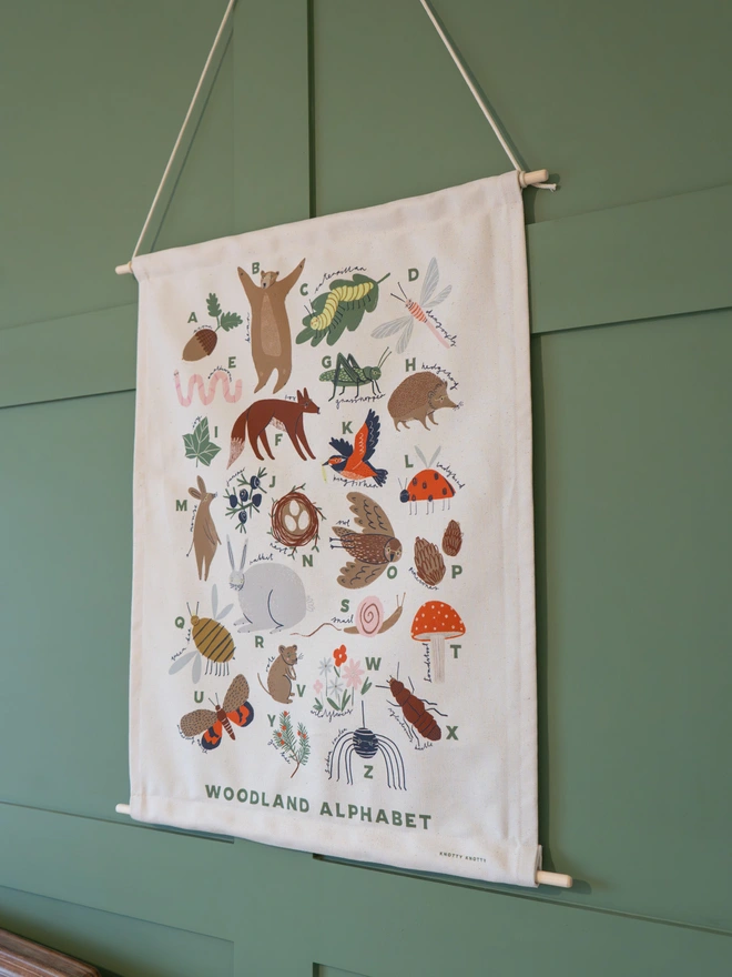 Woodland Alphabet Fabric Banner, against a green wall. 