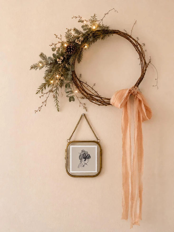 a mini portrait of a little girl in a glass and brass frame hung next to a pretty christmas wreath